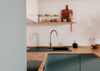 Cuisine rénovée dans un appartement à Montpellier quartier Gambetta, pensée par une architecte d’intérieur avec façades vertes et plan de travail en bois.