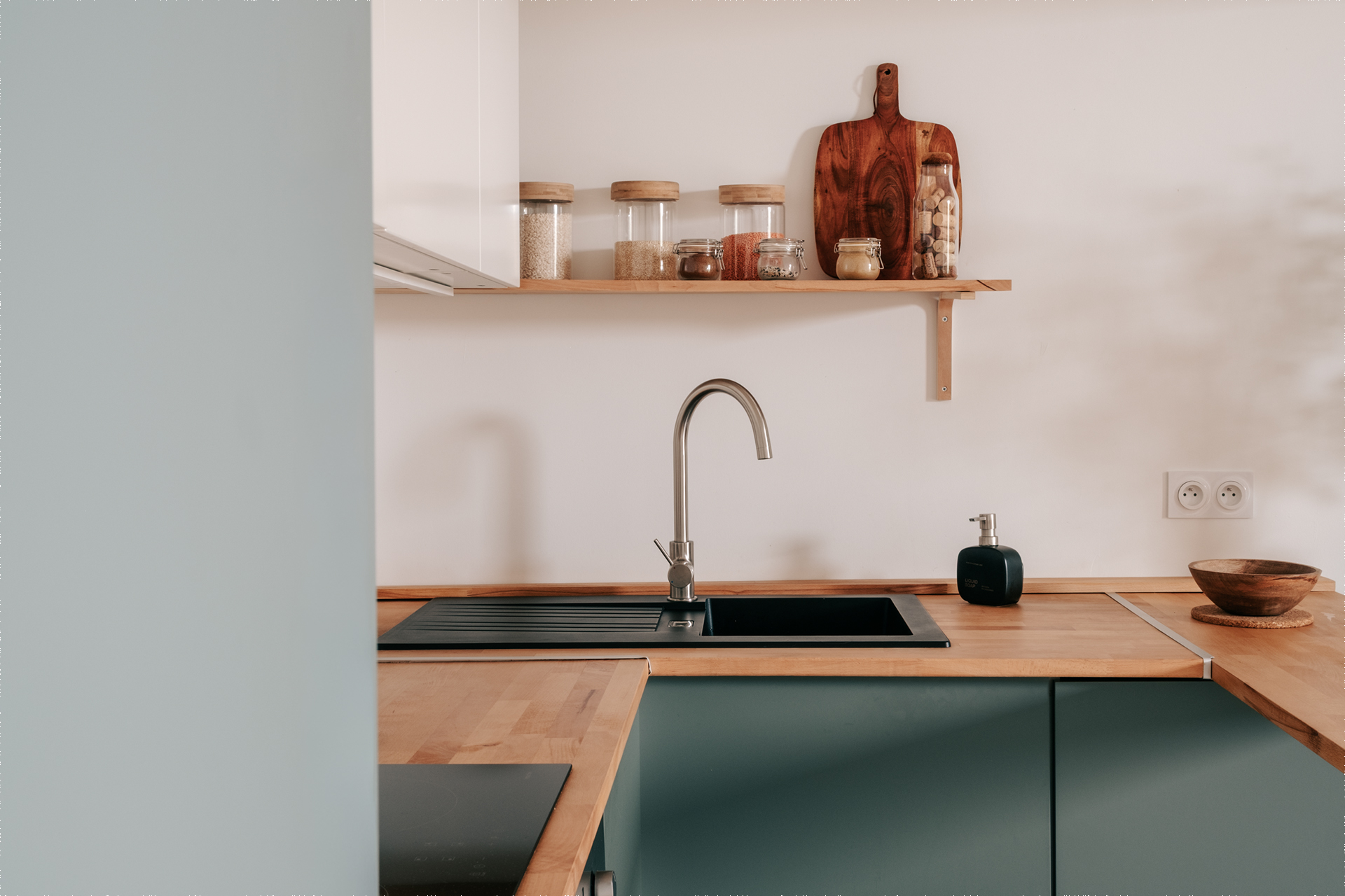 Cuisine rénovée dans un appartement à Montpellier quartier Gambetta, pensée par une architecte d’intérieur avec façades vertes et plan de travail en bois.
